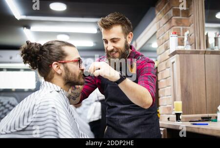 Rasatura barbiere un uomo barbuto in un barbiere, close-up Foto Stock