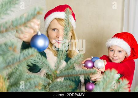 Bionda bella donna che decorano l'albero di natale con le sfere blu di decorazione ornamenti. Foto Stock