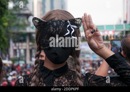 Bangkok, Thailandia. 25 Ott 2020. Un protestore che indossa una maschera, fa il saluto a tre dita durante una dimostrazione all'incrocio di Ratchaprasong. Il saluto a tre dita è un simbolo di proteste anti-governative in Thailandia che significa libertà, libertà e fraternità ispirate ai film dei Giochi della fame. Credit: Peerapon Boonyakiat/SOPA Images/ZUMA Wire/Alamy Live News Foto Stock