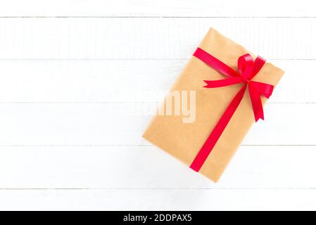 Confezione regalo con nastro rosso su legno bianco, Natale e sfondo festivo Foto Stock