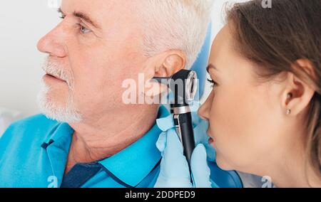 Esame uditivo. Paziente anziano durante un test uditivo, un medico con un otoscopio che controlla l'udito di un paziente anziano, primo piano Foto Stock