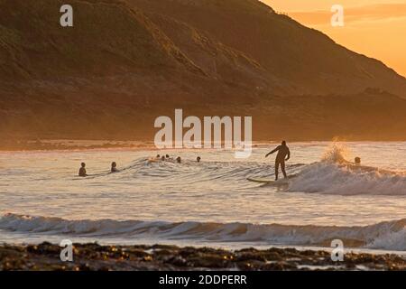 Swansea, Regno Unito. 26 Nov 2020. I Surfers che fanno il la maggior parte del swell come l'oceano è bagnata nel bagliore dorato dell'alba a Langland Bay vicino Swansea questa mattina. Credit: Phil Rees/Alamy Live News Foto Stock