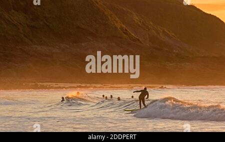 Swansea, Regno Unito. 26 Nov 2020. I Surfers che fanno il la maggior parte del swell come l'oceano è bagnata nel bagliore dorato dell'alba a Langland Bay vicino Swansea questa mattina. Credit: Phil Rees/Alamy Live News Foto Stock
