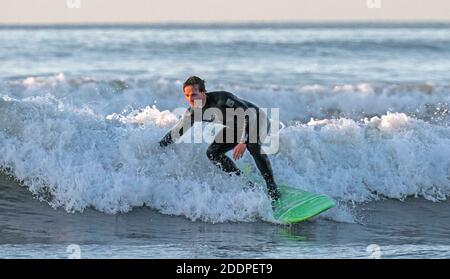 Swansea, Regno Unito. 26 Nov 2020. I Surfers che fanno il la maggior parte del swell come l'oceano è bagnata nel bagliore dorato dell'alba a Langland Bay vicino Swansea questa mattina. Credit: Phil Rees/Alamy Live News Foto Stock