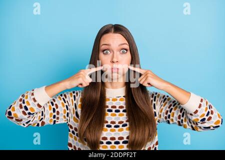 Foto di impressionato divertente donna vestito pullover ornamentale che punta dita guance poued isolato sfondo di colore blu Foto Stock