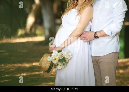 Una giovane e romantica coppia di graziosi futuri genitori che fanno un foto di gravidanza in una foresta Foto Stock