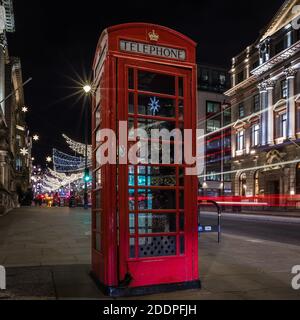 L'albero di natale di St. James si riflette sulla scatola telefonica rossa in Lower Regents Street, Londra. Foto Stock
