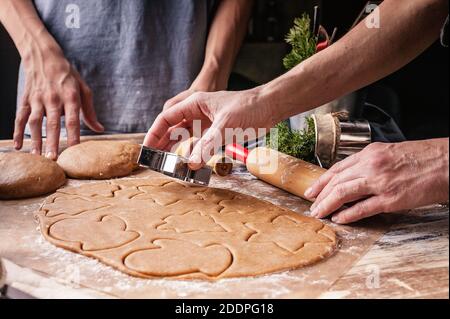 Le mani di mamma e bambini stanno preparando i biscotti di pan di zenzero di Natale. Rustico piano di appoggio. Deliziosi dolci tradizionali fatti in casa Foto Stock