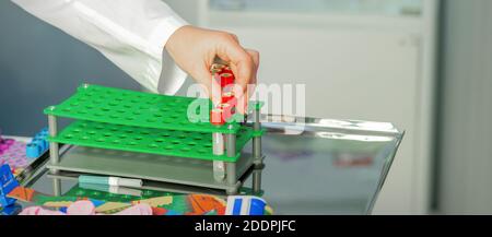La mano del tecnico mette i test della provetta vuota a. un rack in laboratorio Foto Stock