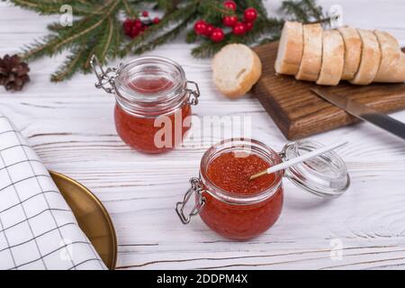 Caviale rosso in cucchiaio su sfondo di legno bianco invecchiato. Piatto principale Capodanno Foto Stock