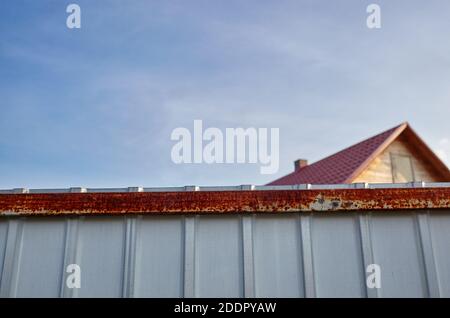 Ferro recinzione arrugginita. Superficie in metallo ondulato bianco o zinco o acciaio galvanizzato sullo sfondo verticale. Foto Stock