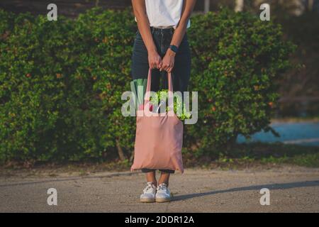 Donna con eco bag riutilizzabile rosa con verdure biologiche fresche. Acquisto di dieta vegana a base di piante. Cibo sano mangiare pulito. Zero rifiuti, senza plastica Foto Stock