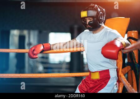 pugile sportivo stanco che riposa nell'anello di boxe ad angolo dopo aver combattuto Foto Stock