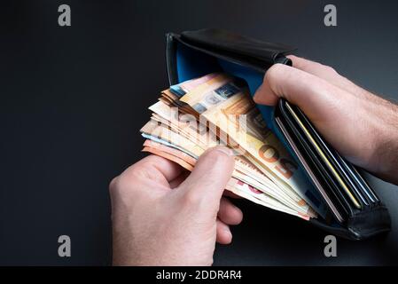 primo piano, alto angolo di visione delle mani di una persona che prende denaro da borsetta o portafoglio Foto Stock