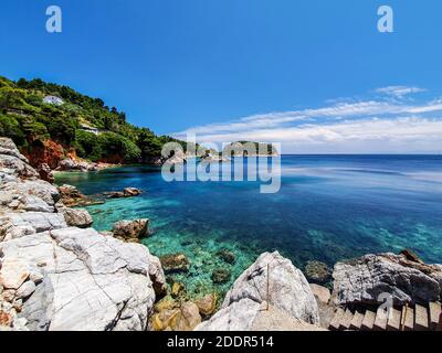 Vista sulla baia di un'isola greca con scogliere e acque cristalline nel Mar Egeo. Foto Stock