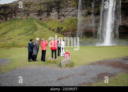 Giovane coppia appena merried durante la celebrazione del matrimonio foto sparare di fronte alle cascate di Skogafoss, Islanda Foto Stock