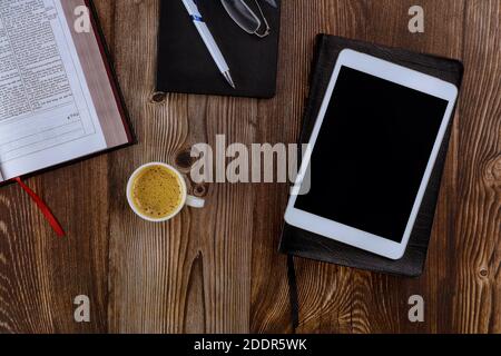 CHICAGO il US 01 LUGLIO 2020: Aprire la Sacra Bibbia adagiata su un tavolo di legno in una lettura la tavoletta digitale con tazza di caffè Foto Stock