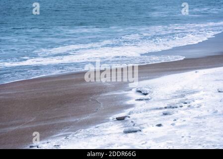 Spiaggia coperta di neve durante una tempesta di neve in luce del giorno Foto Stock
