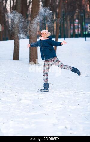 Felice ragazza adolescente che ha una lotta con palla di neve, pronta a lanciare una palla di neve, giocando palle di neve nel parco invernale Foto Stock