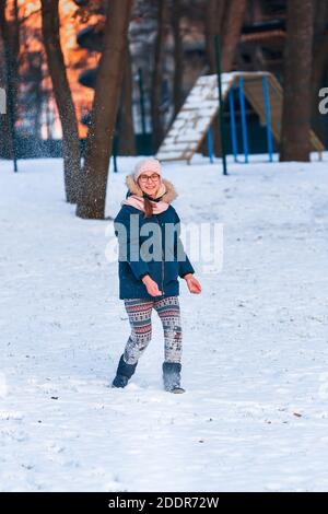 Felice ragazza adolescente che ha una lotta con palla di neve, pronta a lanciare una palla di neve, giocando palle di neve nel parco invernale Foto Stock