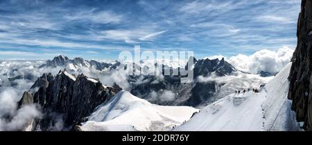 Gli scalatori sul ghiacciaio del Monte Bianco appaiono poco più che puntini neri contro la neve bianca e il maestoso Sfondo della montagna più alta d'Europa Foto Stock