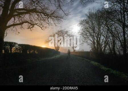 Una figura con gancio trasparente. In piedi su una strada di campagna spooky. In una notte di inverni nebbiosa Foto Stock