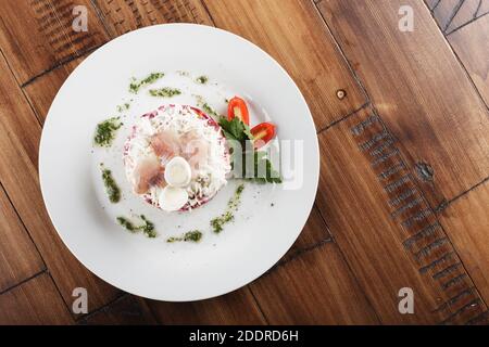 aringa sotto pelliccia cappotto insalata russa. sfondo di legno Foto Stock