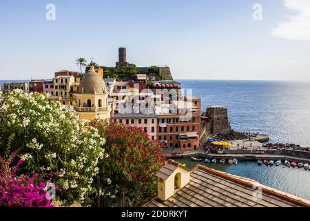 Vernazza, Italia - 8 luglio 2017: Veduta della Chiesa di Santa Margherita d'Antiochia con case colorate e Castello di Doria sullo sfondo Foto Stock