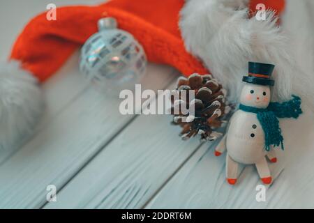 Natale legno pupazzo di neve bianco legno sfondo con giocattolo d'epoca in miniatura, cono di pino, ornamento palla di vetro e cappello di santa per vacanze di Natale Foto Stock