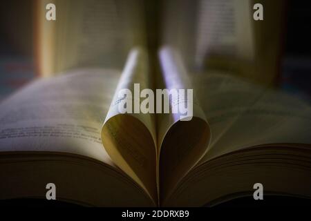 Un primo piano di un libro aperto con un cuore fatto dalle sue pagine Foto Stock