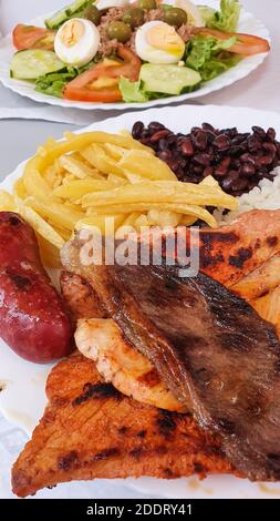 Primo piano di bistecche grigliate miste su un piatto, con carne di maiale, manzo, pollo e patate, fuoco selettivo, verticale Foto Stock