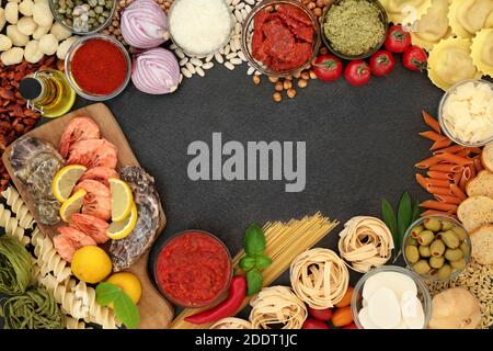 Alimenti mediterranei ingredienti per una dieta sana con frutti di mare, pasta, salse, verdure, erbe, legumi, olio d'oliva e formaggi. Bordo su ardesia. Foto Stock