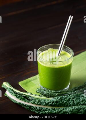 Bicchiere di succo vegetale biologico fresco con Dino kale su superficie in legno con cannuccia in acciaio inox; spazio per la copia Foto Stock