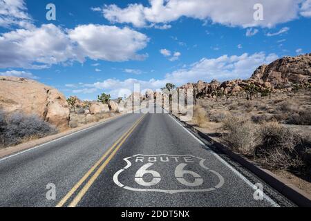 La strada del deserto della California Joshua Tree con il cartello stradale della Route 66 e le nuvole. Foto Stock