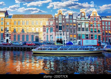 Vista classica di Amsterdam : edifici medievali , canale , barca , e riflessione in acqua. Tramonto Foto Stock