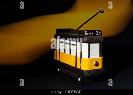 Piccolo modello in legno del tram giallo 28 di Lisbona con effetto luminoso sullo sfondo. Foto Stock