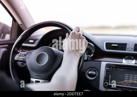 Un uomo guida un'auto, una mano sul volante, una vista dall'interno. Foto Stock