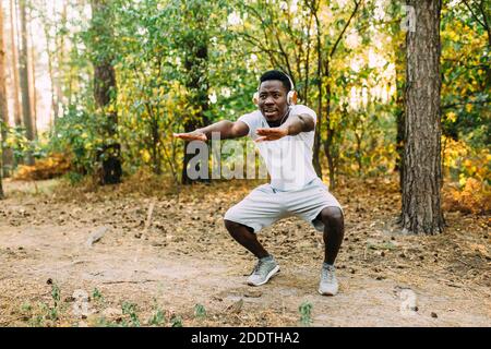 Atletico afroamericano, corridore che fa esercizi di stretching, preparandosi per l'allenamento mattutino nel Parco Foto Stock