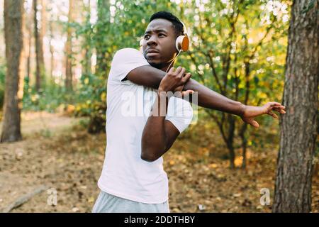 Atletico afroamericano, corridore che fa esercizi di stretching, preparandosi per l'allenamento mattutino nel Parco Foto Stock