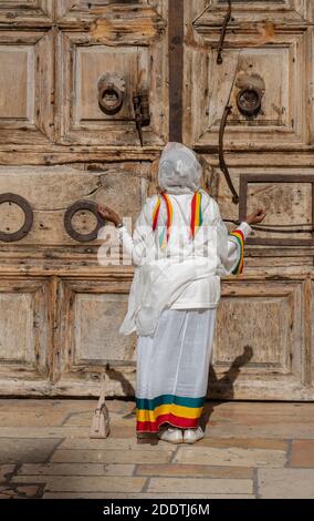 Gerusalemme, Israele - 21 novembre 2020: Una donna che prega alle porte chiuse della chiesa del santo sepolcro, Gerusalemme, Israele. Foto Stock