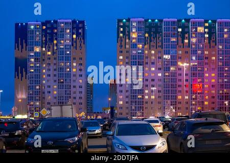 Surgut, Russia - 10.13.2019:edifici alti della città notturna e un parcheggio contro un cielo blu scuro Foto Stock
