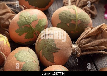 Uova di Pasqua con erbe attaccate a loro con calze, pronte per essere tinte con bucce di cipolla Foto Stock