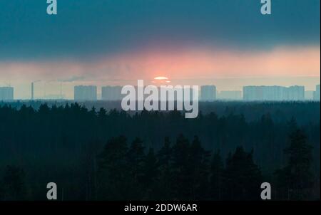 Il sole tramonta dietro le case della città . Regione di Leningrad. Foto Stock