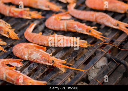 Processo di cottura dei gamberi rossi di langoustina freschi, gamberi alla griglia - cibo di strada Foto Stock