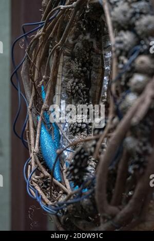 Un dettaglio di una composizione natalizia. Materiali naturali (vimini, ramoscelli, coni di pino) e accessori artificiali (filo blu, giocattolo lucido in plastica blu Foto Stock