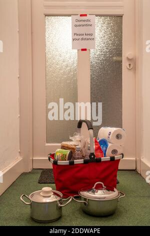 Immagine simbolica quarantena domestica, l'uomo è sospettato di infezione corona, a casa in isolamento, segnale di avvertimento per i visitatori alla porta piatta, comunicat Foto Stock