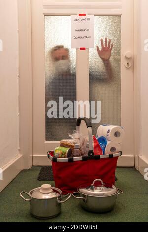 Immagine simbolica quarantena domestica, l'uomo è sospettato di infezione corona, a casa in isolamento, segnale di avvertimento per i visitatori alla porta piatta, comunicat Foto Stock