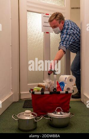 Immagine simbolica quarantena domestica, l'uomo è sospettato di infezione corona, a casa in isolamento, segnale di avvertimento per i visitatori alla porta piatta, comunicat Foto Stock