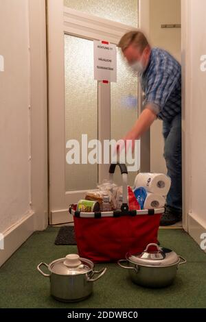 Immagine simbolica quarantena domestica, l'uomo è sospettato di infezione corona, a casa in isolamento, segnale di avvertimento per i visitatori alla porta piatta, comunicat Foto Stock