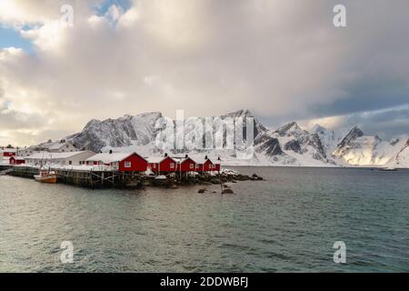 Paesaggio delle Isole Lofoten in Norvegia con legno tradizionale capanne di pescatori rossi di fronte al mare e questo bella moutain sullo sfondo Foto Stock
